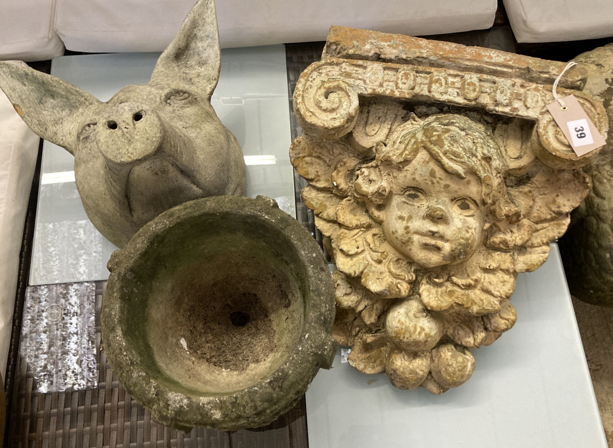 A terracotta pigs head wall applique, height 28cm, a composition bracket and a stone urn